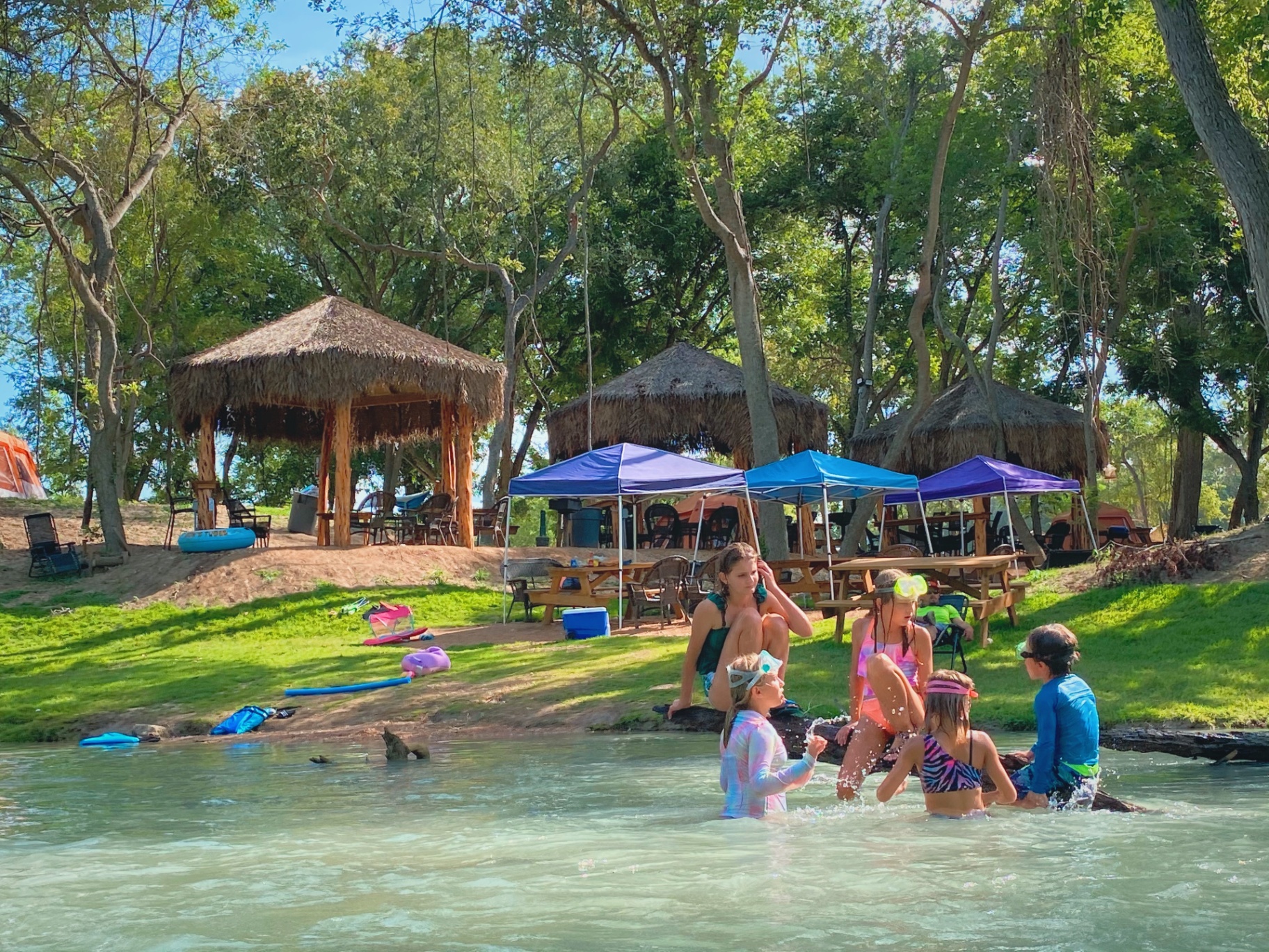 Kids swimming near riverside cabanas