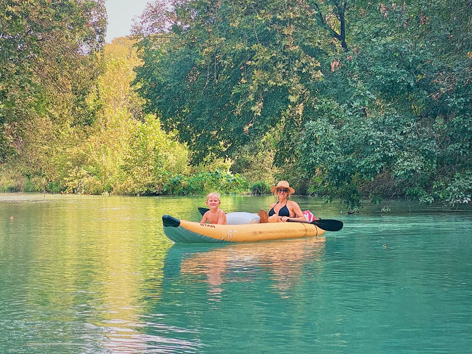 Mom and son kayaking on calm river