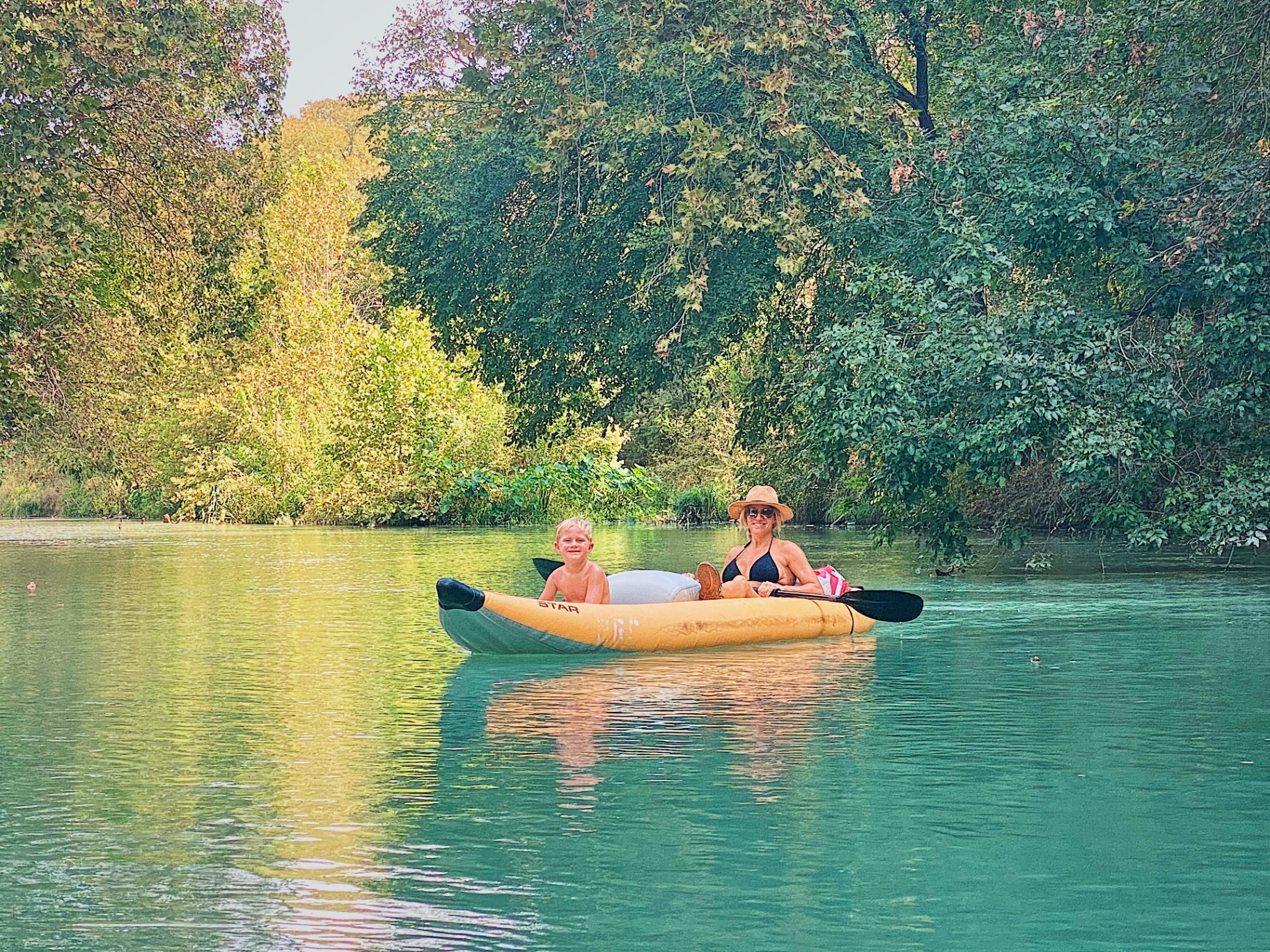 Mom and son kayaking on calm river